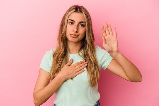 Jeune femme blonde de race blanche prêtant serment, mettant la main sur la poitrine.