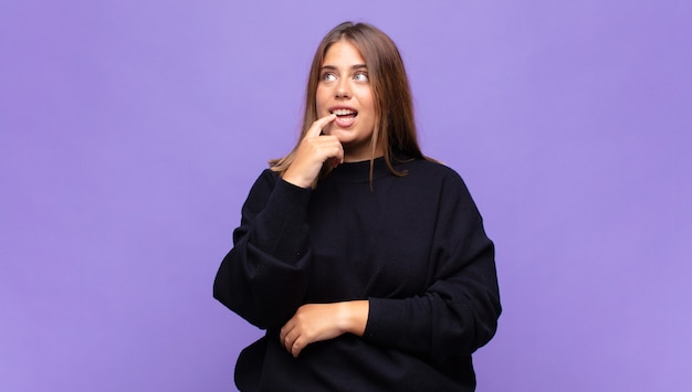 Jeune femme blonde avec un regard surpris, nerveux, inquiet ou effrayé, regardant sur le côté vers l'espace de copie