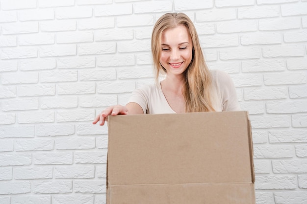 Jeune femme blonde regardant dans la boîte de livraison avec un fond blanc