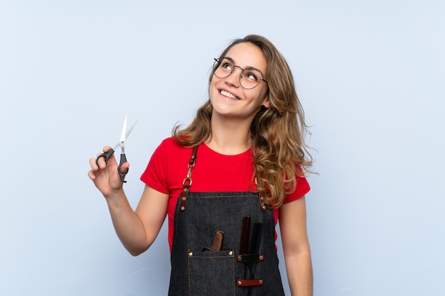 Jeune femme blonde avec une robe de coiffeur ou un coiffeur levant