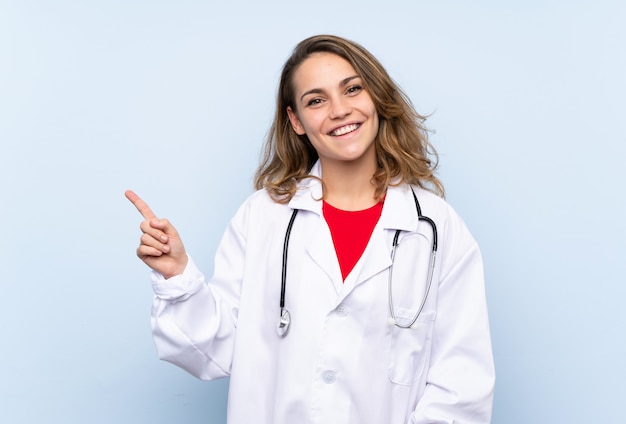 Jeune femme blonde avec une robe de docteur et pointant le côté