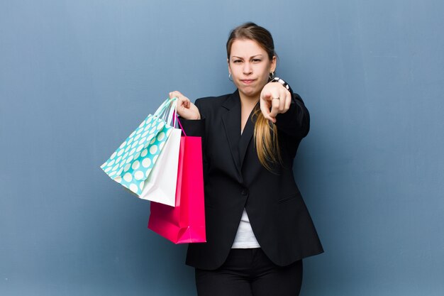 Jeune femme blonde avec des sacs à provisions contre le mur de grunge