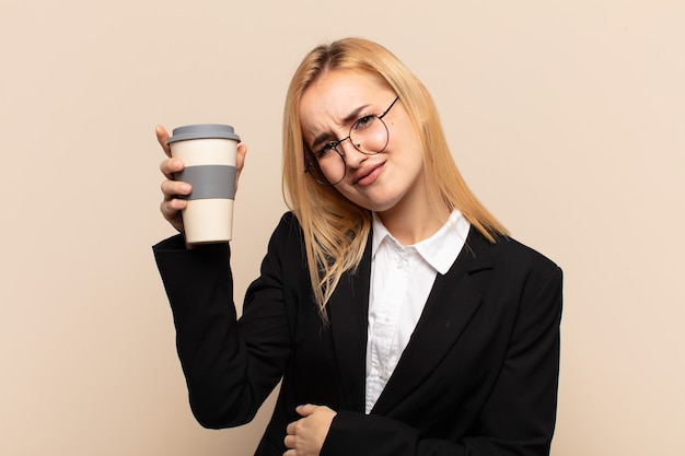 Jeune femme blonde se sentant anxieuse, malade, malade et malheureuse, souffrant de maux d'estomac ou de grippe