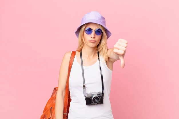 Jeune femme blonde se sentant croisée, montrant les pouces vers le bas