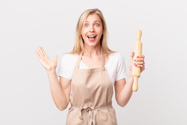 Jeune femme blonde se sentant heureuse et étonnée de quelque chose d'incroyable. concept de boulanger