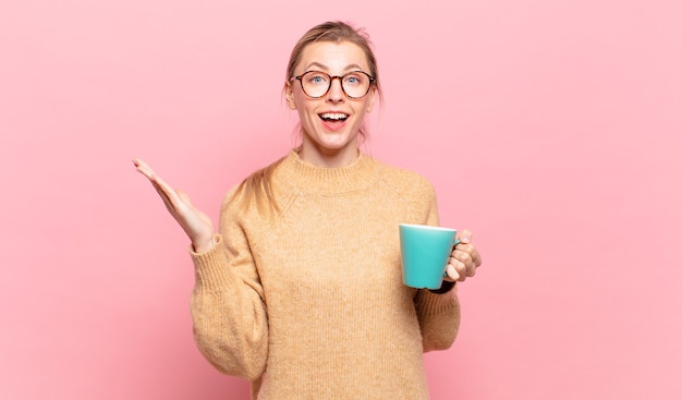 Jeune femme blonde se sentant heureuse, surprise et joyeuse, souriante avec une attitude positive, réalisant une solution ou une idée