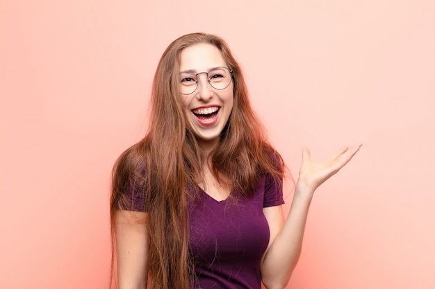 Jeune femme blonde se sentant heureuse, surprise et joyeuse, souriante avec une attitude positive, réalisant une solution ou une idée