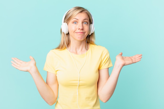 Jeune femme blonde se sentant perplexe et confuse et doutant et écoutant de la musique.