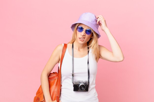 Jeune femme blonde se sentant perplexe et confuse, se grattant la tête