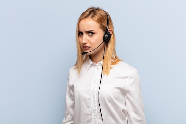 Jeune femme blonde se sentant triste, contrariée ou en colère et regardant de côté avec une attitude négative, fronçant les sourcils en désaccord