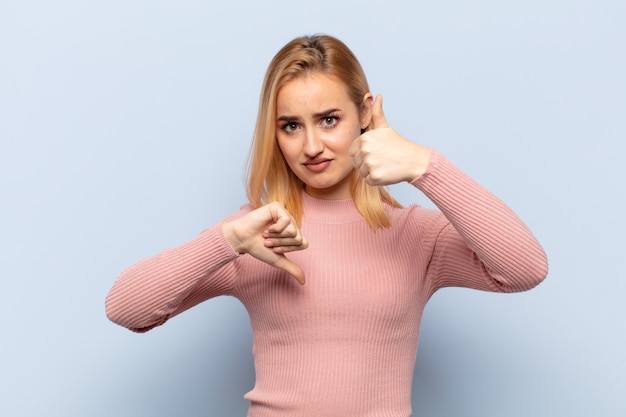 Photo jeune femme blonde se sentir confus, désemparé et incertain, pondérant le bien et le mal dans différentes options ou choix