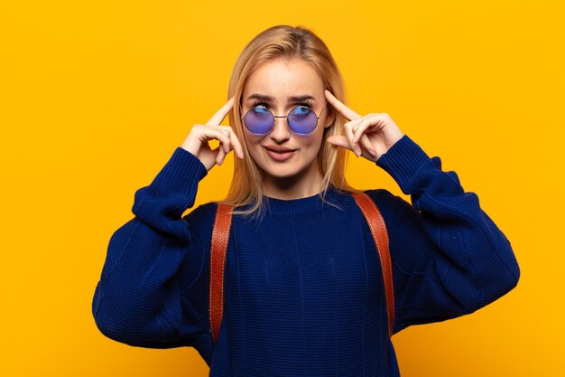 Jeune femme blonde se sentir confus ou douter, se concentrer sur une idée, réfléchir, à la recherche de copier l'espace sur le côté