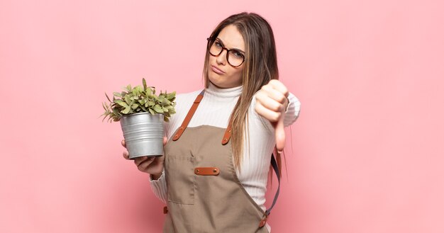 Jeune femme blonde se sentir croisé, en colère, ennuyé, déçu ou mécontent, montrant les pouces vers le bas avec un regard sérieux