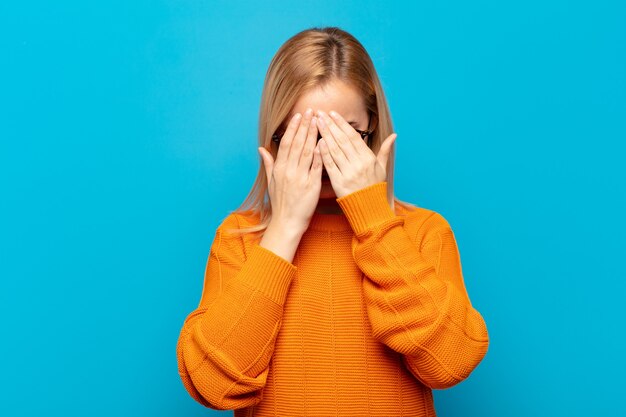 Jeune femme blonde se sentir triste, frustré, nerveux et déprimé, couvrant le visage à deux mains, pleurant