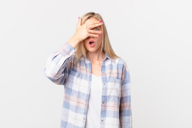 Photo jeune femme blonde semblant choquée, effrayée ou terrifiée, couvrant le visage avec la main