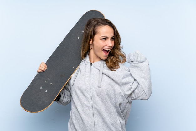 Jeune femme blonde avec skate et geste de victoire