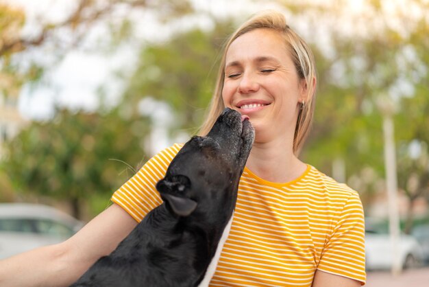 Une jeune femme blonde avec son adorable chien noir à l'extérieur