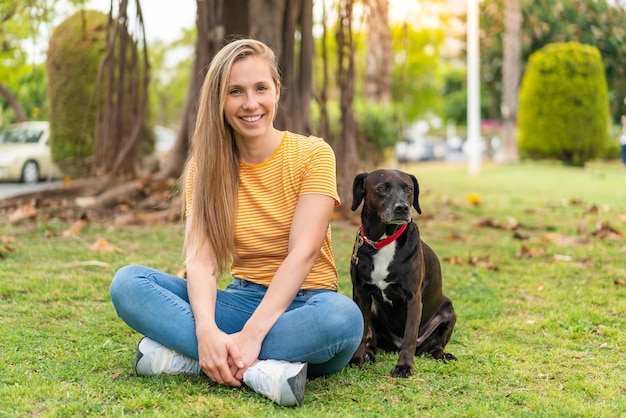 Une jeune femme blonde avec son adorable chien noir à l'extérieur