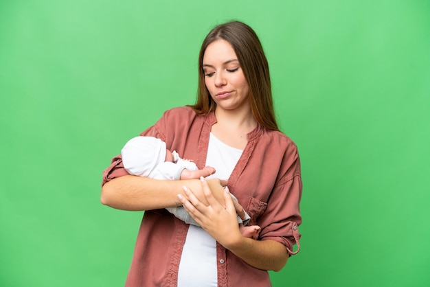 Jeune femme blonde avec son bébé nouveau-né sur fond isolé chroma key avec une expression triste