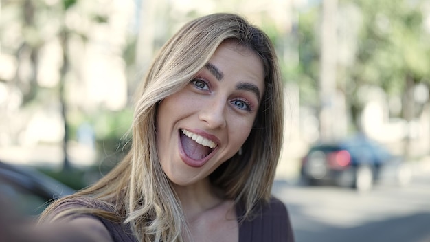 Jeune femme blonde souriante confiante debout au parc