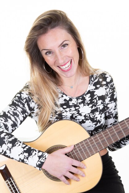 Jeune femme blonde souriante avec une guitare sur blanc