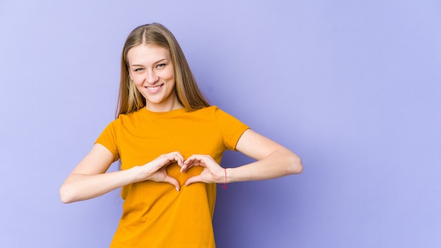 Jeune femme blonde souriante et montrant une forme de coeur avec les mains