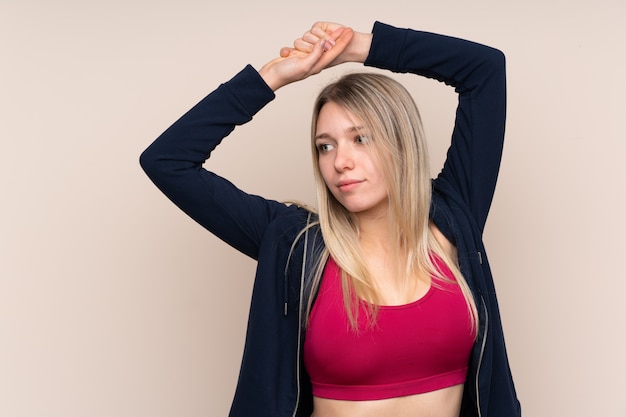 Jeune femme blonde sport sur mur isolé qui s'étend