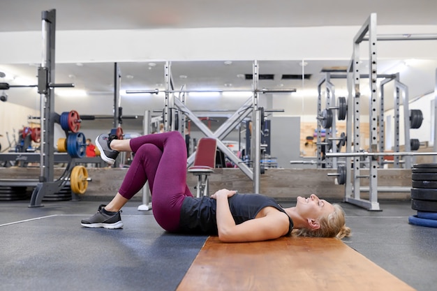 Jeune femme blonde sportive qui s'étend du corps tout en faisant des exercices de yoga au gymnase