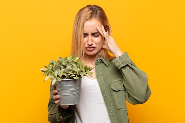 Jeune femme blonde à la stress et frustré, travaillant sous pression avec un mal de tête et troublé par des problèmes