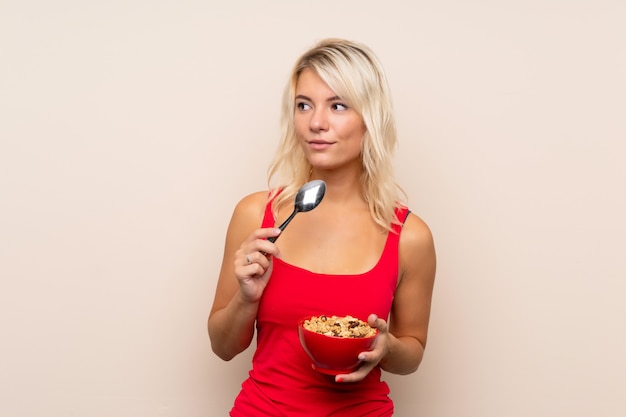 Jeune femme blonde tenant un bol de céréales et de penser