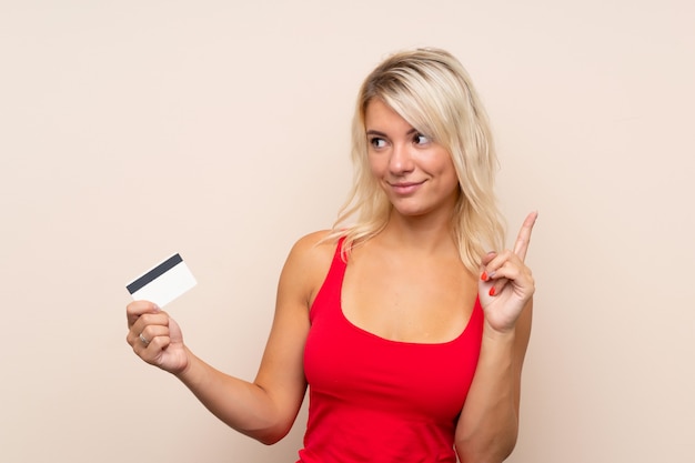 Jeune femme blonde tenant une carte de crédit