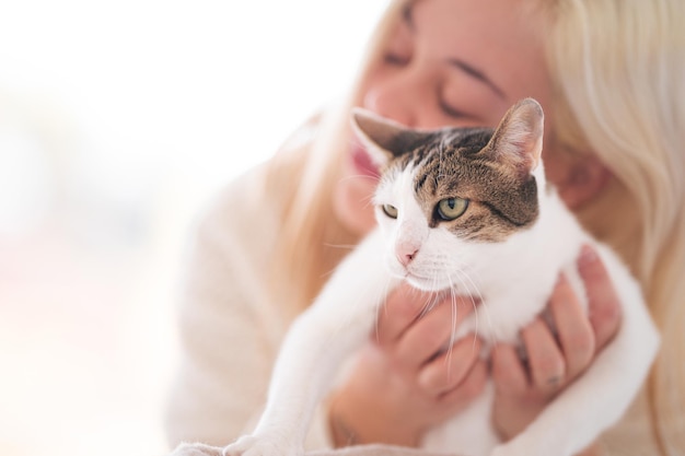 Jeune femme blonde tenant un chat blanc sur un fond lumineux