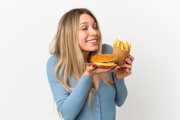 Jeune femme blonde tenant des frites et cheeseburger sur fond isolé