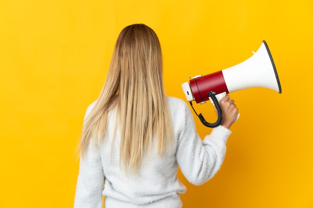 Jeune femme blonde tenant un mégaphone et en position arrière