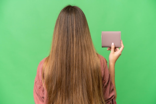 Jeune femme blonde tenant un portefeuille sur fond isolé chroma key en position arrière