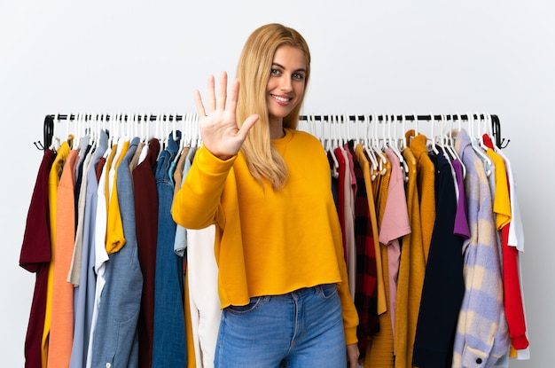 Jeune femme blonde uruguayenne dans un magasin de vêtements comptant cinq avec les doigts