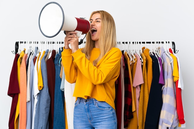 Jeune femme blonde uruguayenne dans un magasin de vêtements criant à travers un mégaphone