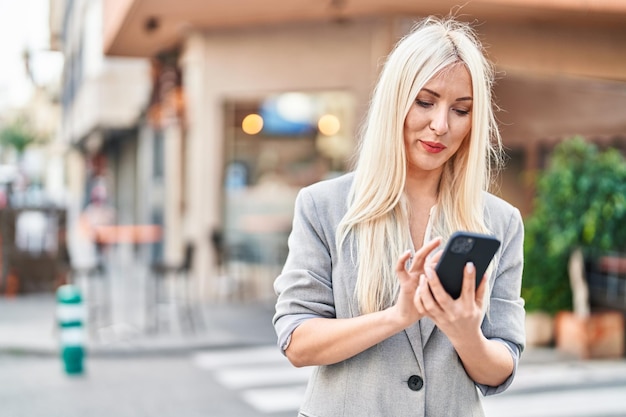 Jeune femme blonde utilisant un smartphone dans la rue