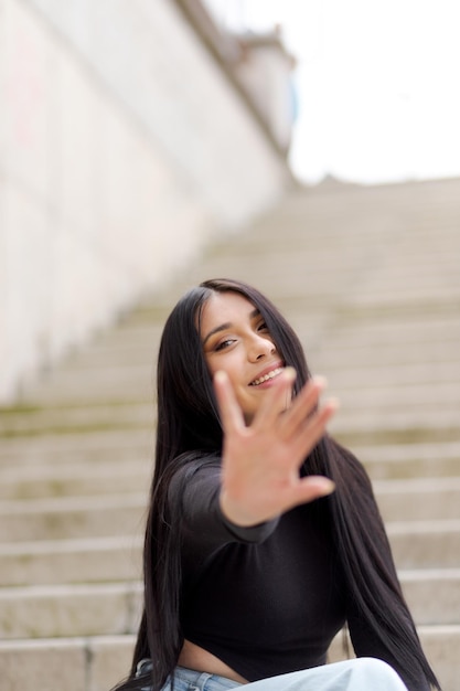 Jeune femme bloquant la caméra avec la main Heureux jeune homme souriant joyeusement à la caméra assis à l'extérieur dans les escaliers de la rue