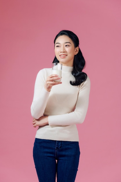 Jeune femme boire un verre de lait femme sourire heureux isolé sur fond rose