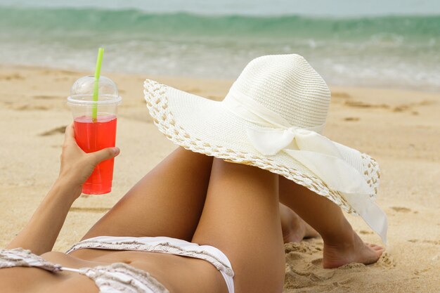 Jeune femme avec une boisson rafraîchissante rouge sur la plage