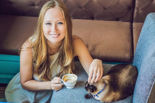 La jeune femme boit du café et caresse le chat