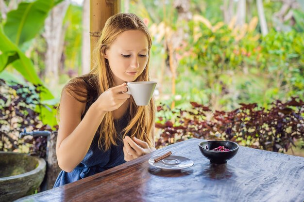 Jeune femme boit du café Luwak dans le belvédère.