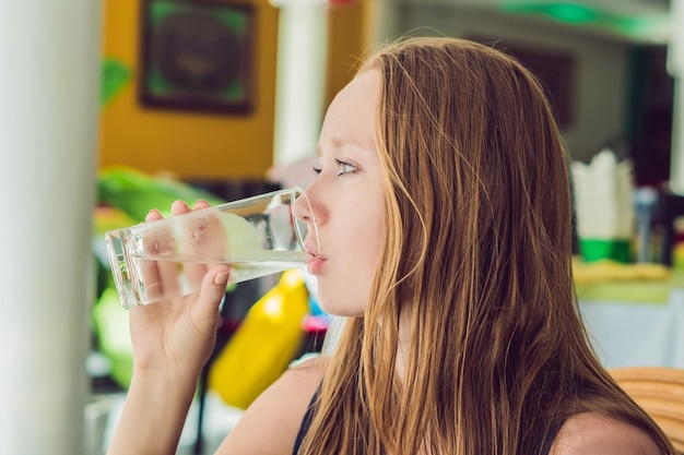 Jeune femme boit de l'eau dans un café.