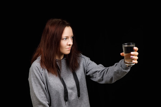 Jeune femme boit de l'eau pure et propre dans le verre