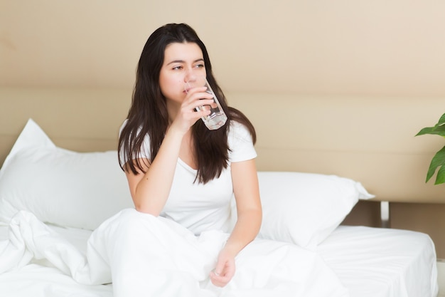 Jeune femme boit un verre d'eau le matin, concept de mode de vie sain