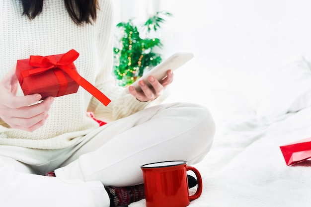 Jeune Femme Avec Boîte-cadeau Rouge Et Téléphone Dans Les Mains Et Tasse Rouge De Boisson