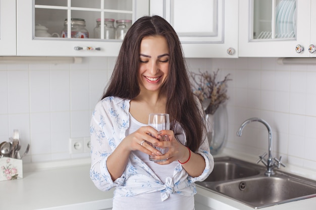 Jeune femme en bonne santé, boire de l'eau filtrée sur la cuisine