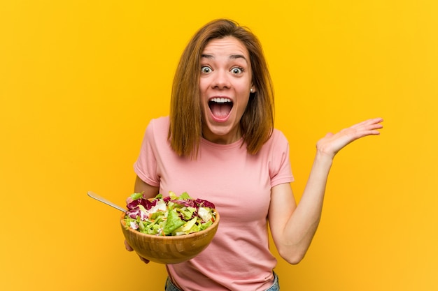 Jeune femme en bonne santé tenant une salade célébrant une victoire ou un succès