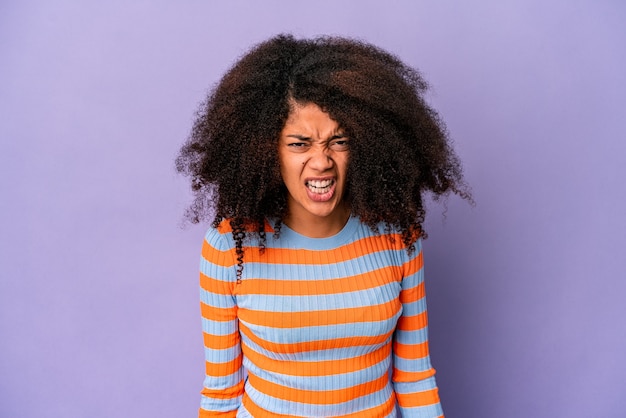 Jeune femme bouclée afro-américaine isolée sur mur violet criant très en colère, concept de rage, frustré.
